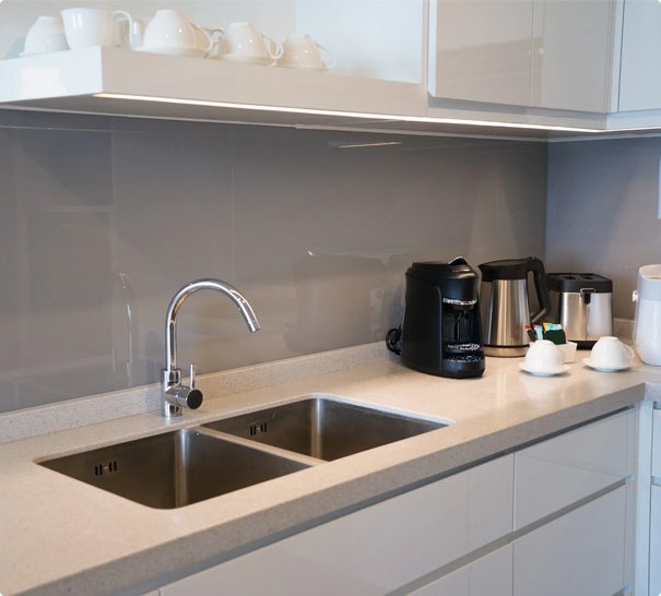 Modern kitchen interior with double sink, chrome faucet, and coffee appliances on countertop.