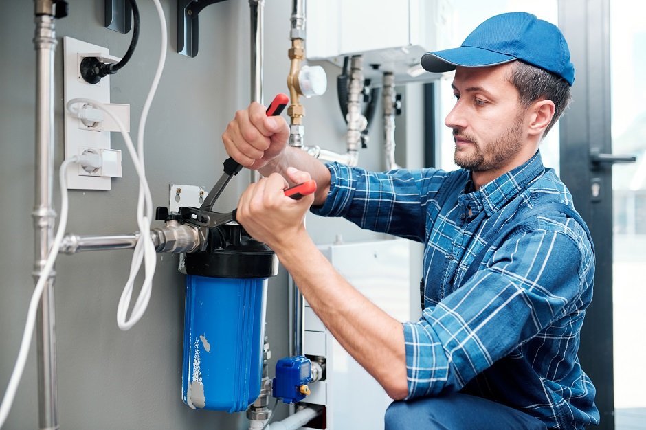 Plumber installing or repairing a water filtration system using tools